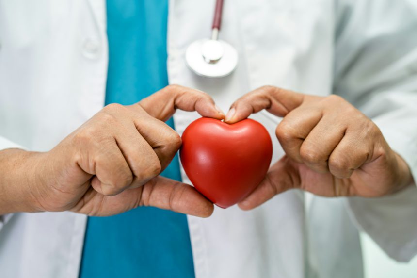 Doctor holding a red heart in hospital ward, healthy strong medical concept.